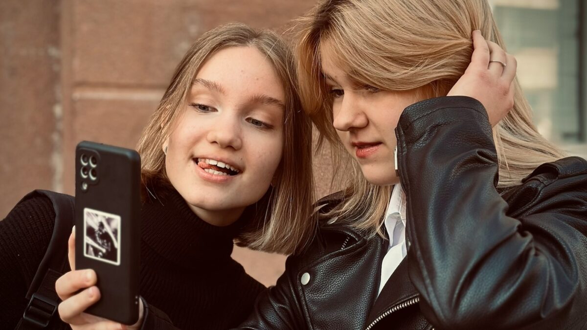 two girls in black looking at smartphone