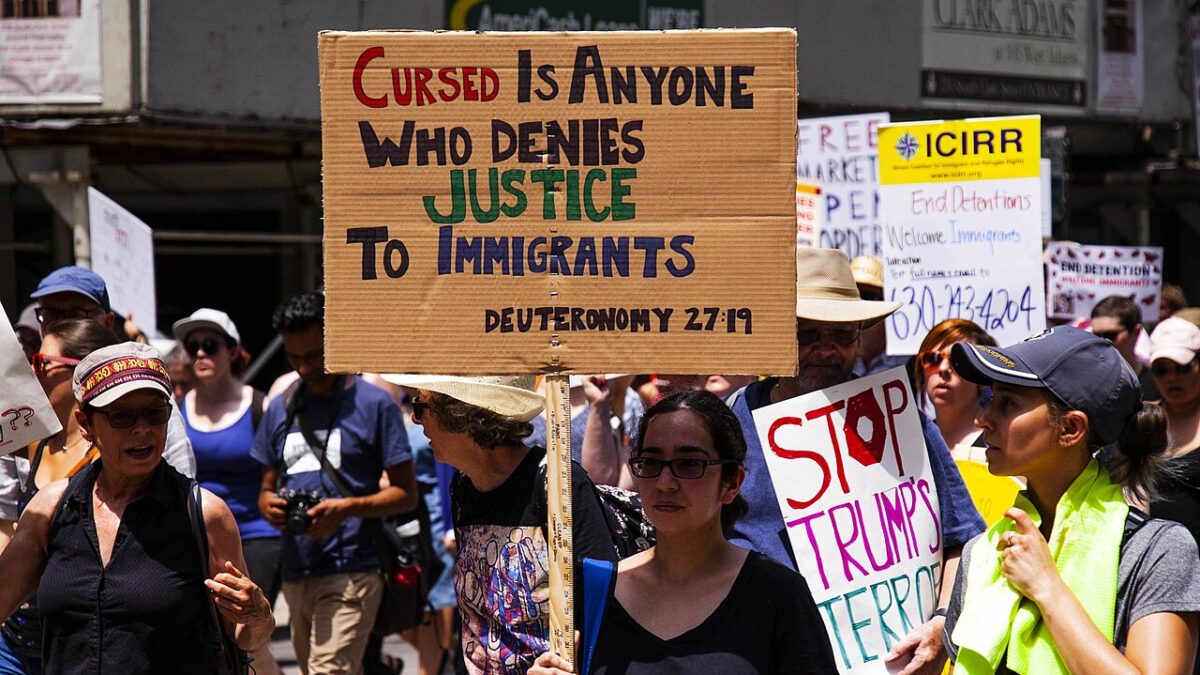 protester carrying Bible or Christian sign against deportation