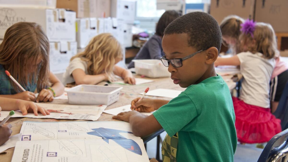 boy in green shirt working on lesson at desk