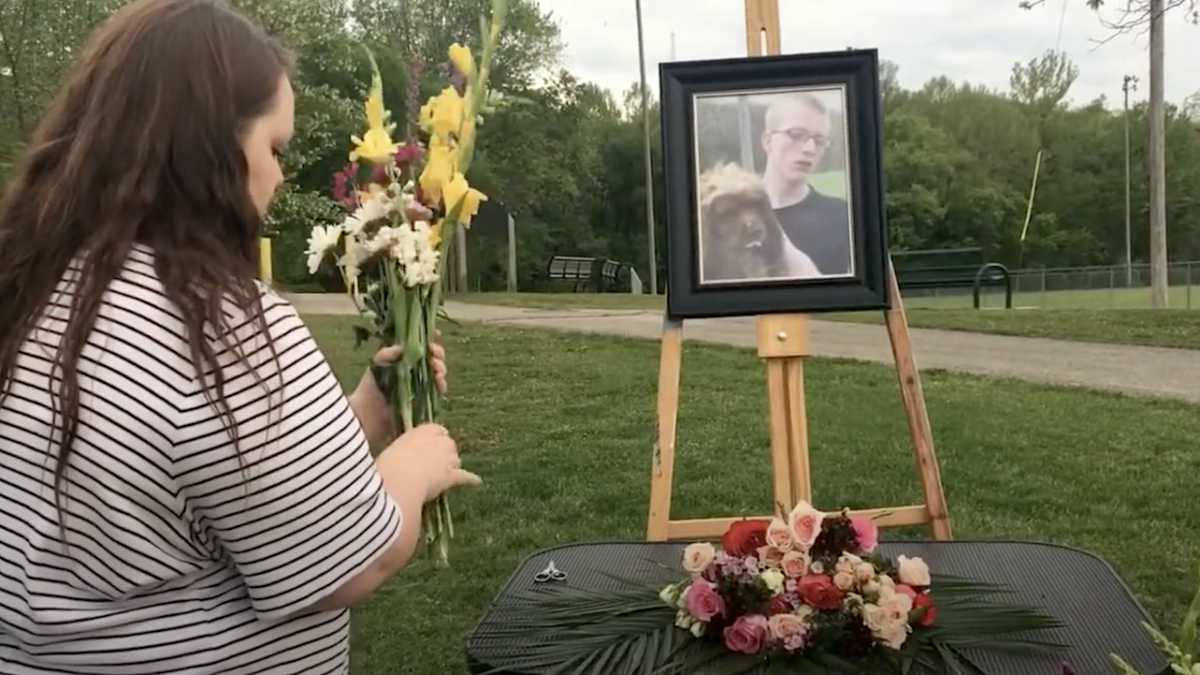 woman lays flowers at Carl DeBrodie memorial