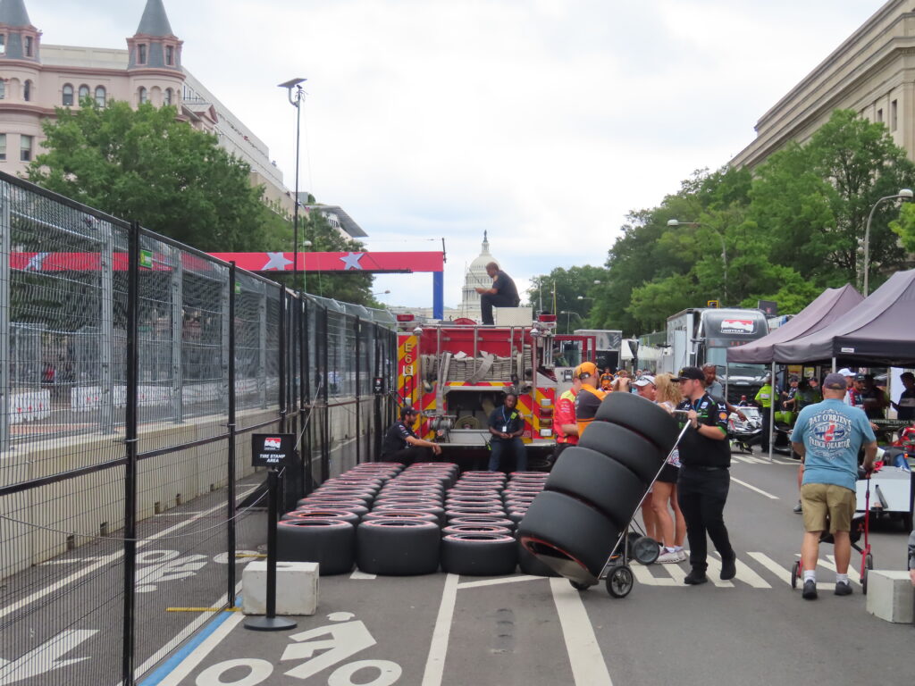 man loading tires behind grand prix track
