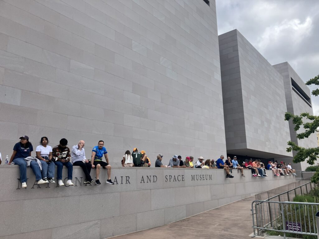spectators gathered sitting on air and space museum ledge