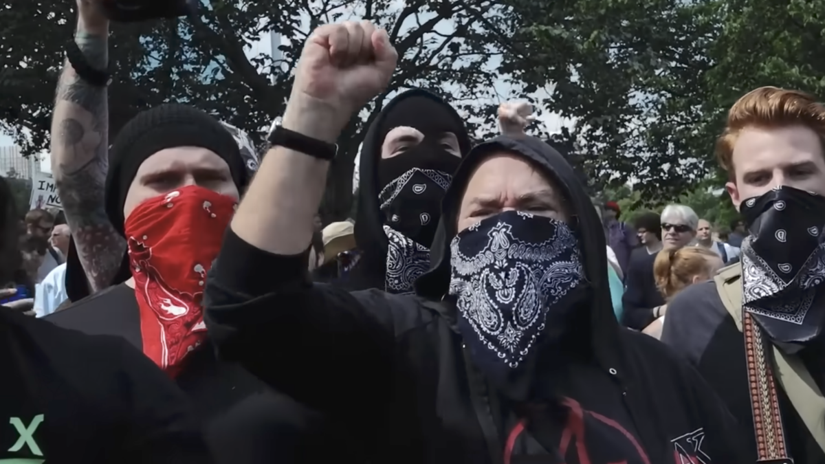 woman wearing bandana face covering chanting in crowd