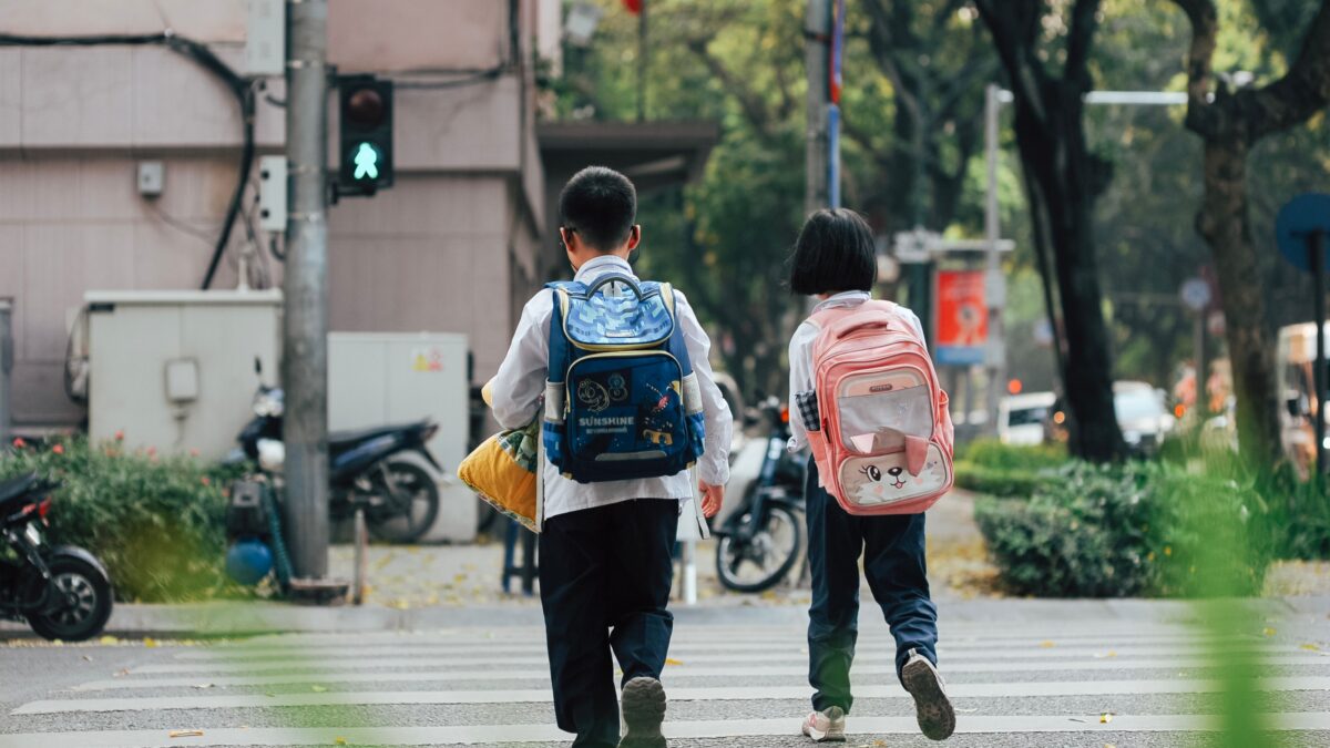 children with backpacks crossing the street