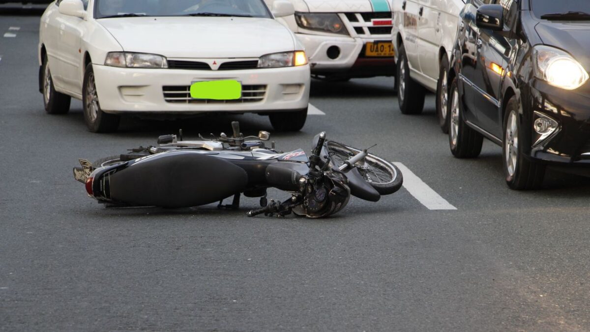 motorcycle lying on road in front of another car