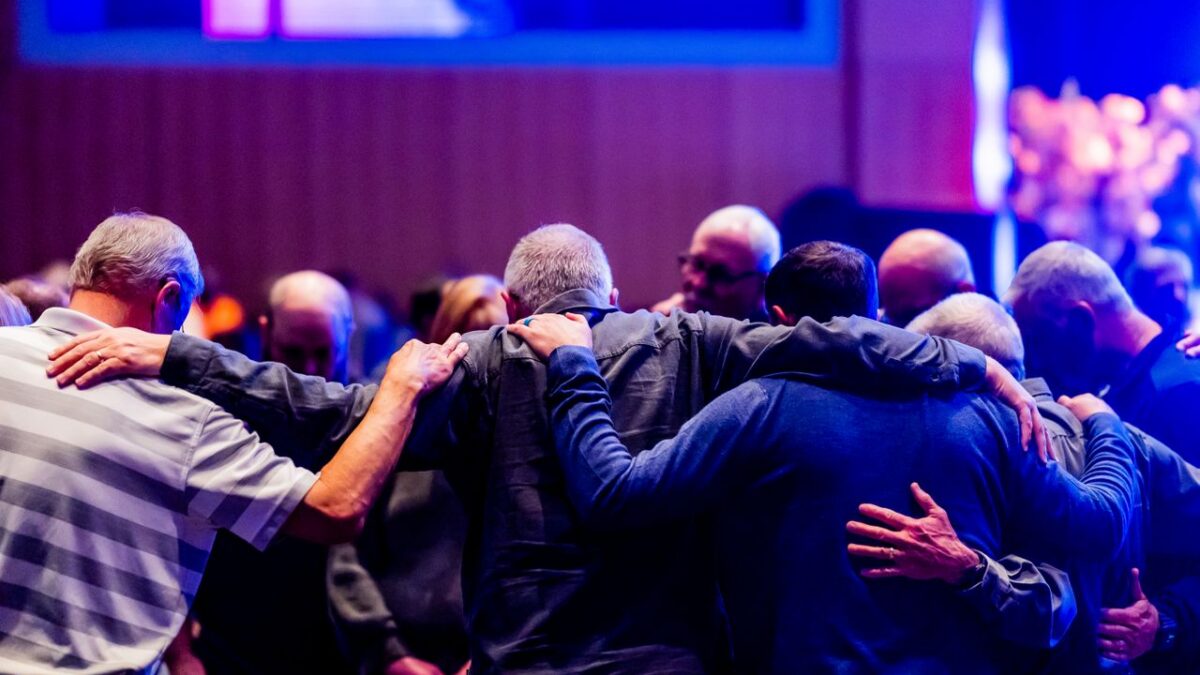 men praying in circle in church service